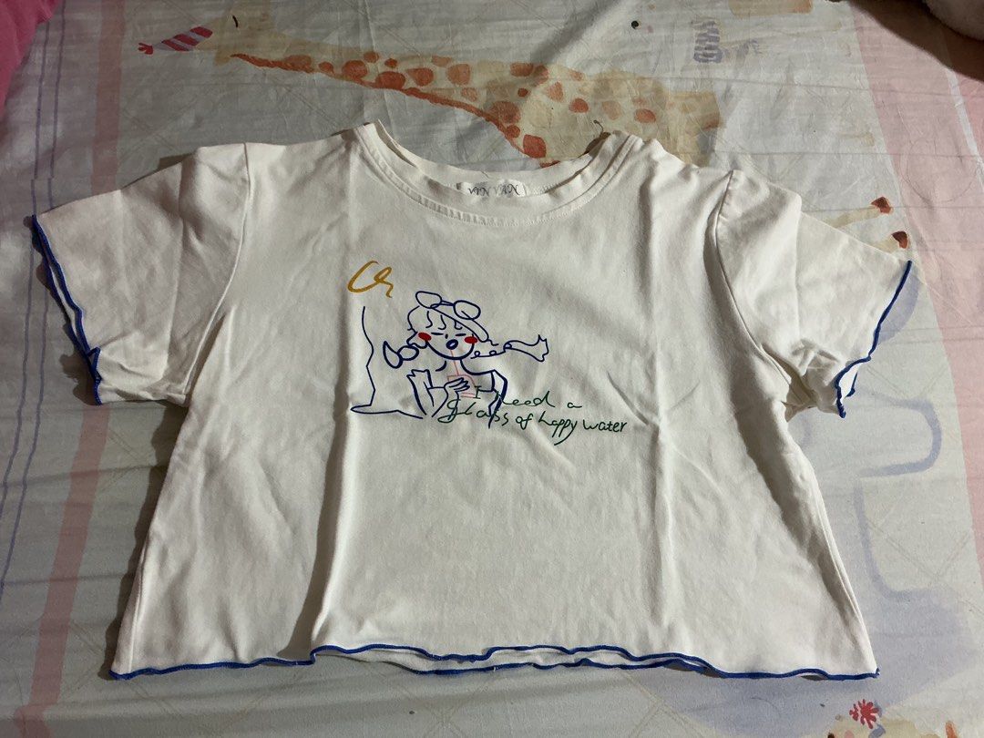 White Graphic Crop Tee Lettuce Hem (Category: Shirts) located in Manila. Submitted by nagsesell (Listing ID 1468743812, Image 1). Description: - Color: White with blue lettuce trim - Design: Playful 'I need a glass of happy water' front graphic - Fit: Relaxed boxy crop top - Details: Contrasting blue lettuce edging on collar, sleeves, and hem - Material: Lightweight cotton, perfect for everyday casual wear.