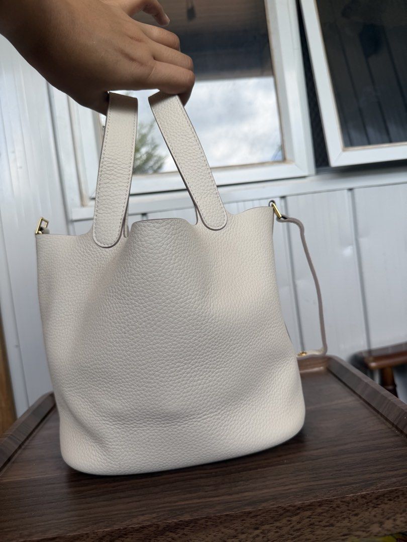 White Leather Bucket Bag with Top Handles (Category: Shoulder Bags) located in Digos. Submitted by old_soul. (Listing ID 1468725362, Image 3). Description: - Material: White pebbled leather with gold hardware - Design: Clean minimalist bucket bag with vertical back strap detailing - Base: Structured oval base with four protective metal feet - Straps: Dual top handles and a thin shoulder strap - Interior: Roomy compartment for all your everyday es