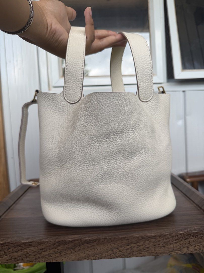 White Leather Bucket Bag with Top Handles (Category: Shoulder Bags) located in Digos. Submitted by old_soul. (Listing ID 1468725362, Image 1). Description: - Material: White pebbled leather with gold hardware - Design: Clean minimalist bucket bag with vertical back strap detailing - Base: Structured oval base with four protective metal feet - Straps: Dual top handles and a thin shoulder strap - Interior: Roomy compartment for all your everyday es