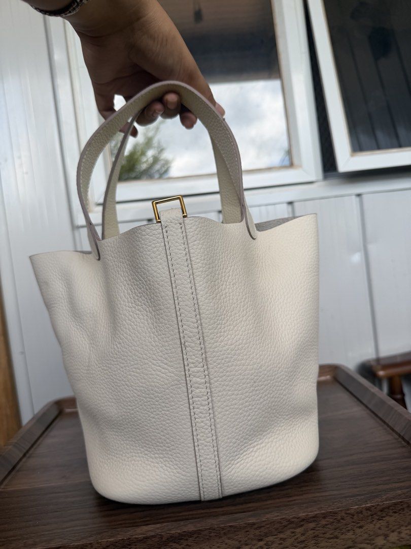 White Leather Bucket Bag with Top Handles (Category: Shoulder Bags) located in Digos. Submitted by old_soul. (Listing ID 1468725362, Image 2). Description: - Material: White pebbled leather with gold hardware - Design: Clean minimalist bucket bag with vertical back strap detailing - Base: Structured oval base with four protective metal feet - Straps: Dual top handles and a thin shoulder strap - Interior: Roomy compartment for all your everyday es