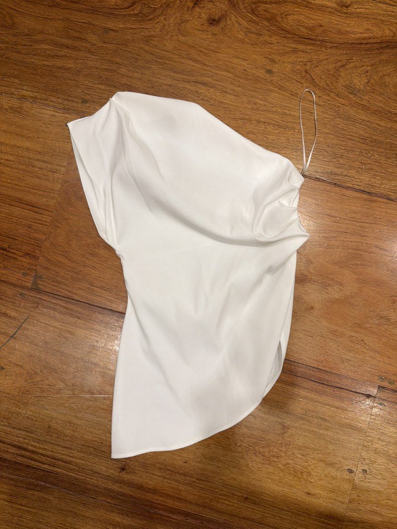 White One Shoulder Satin Top (Category: Blouses) located in Quezon City. Submitted by nic.man (Listing ID 1468863546, Image 1). Description: - Color: White - Material: Smooth satin fabric - Design: One-shoulder with asymmetric neckline and draped front - Strap: Thin spaghetti strap on the right side - Length: Hip-length with a curved hem.