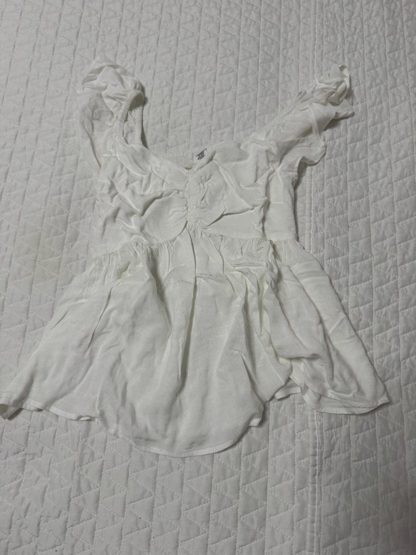 White Ruched Peplum Blouse with Ruffle Straps (Category: Sleeveless) located in Manila. Submitted by mattigarciaa (Listing ID 1468776890, Image 1). Description: - Color: Classic White - Style: Sleeveless top with square neckline - Details: Ruffled shoulders, gathered front, and soft peplum hem - Material: Lightweight and breathable fabric - Fit: Flattering flare at the waist - Condition: Excellent / Like new - Perfect for: Warm-weather styling an