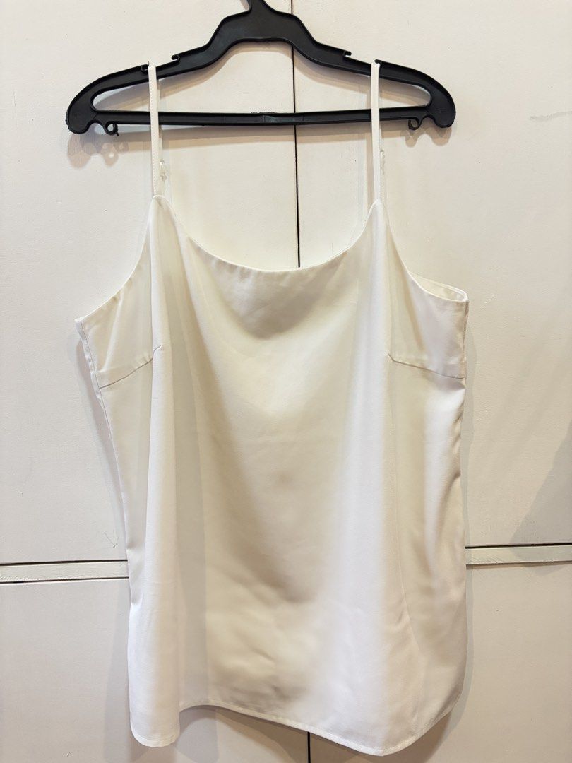 White satin camisole (Category: Sleeveless) located in Caloocan City. Submitted by joannarms320722 (Listing ID 1468780885, Image 2). Description: - Color: White - Material: Smooth and shiny satin fabric - Design: Elegant cowl neckline and adjustable spaghetti straps - Versatility: Perfect to wear solo with jeans/skirts or as a layering piece under cardigans and blazers - Condition: Clean and in great shape.