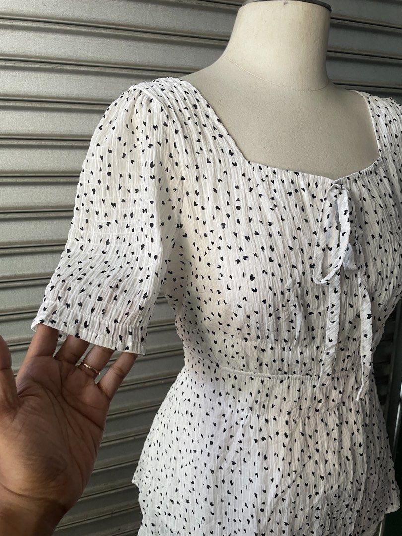 White Square Neck Blouse with Black Hearts (Category: Blouses) located in Davao. Submitted by riab_qt (Listing ID 1468775820, Image 2). Description: White short sleeve blouse with small black heart pattern all over. Square neckline with a tie ribbon detail in the front. Smocked, textured fabric from top to hem. Short puffed sleeves with elastic cuffs. Fitted bodice that flares slightly at the waist. Great casual piece, easy to match with skirts o