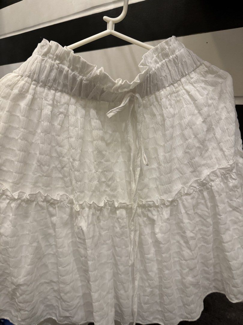 White textured ruffled tiered mini skirt with drawstring waist (Category: Skirts) located in Manila. Submitted by carmela_andd (Listing ID 1468857488, Image 3). Description: - Color: White - Style: Mini skirt with tiered ruffles - Fabric: Lightweight, crinkled texture - Waistband: Comfy elastic with a matching drawstring tie - Perfect for: Warm weather days, casual outings, pairing with tanks or tees.