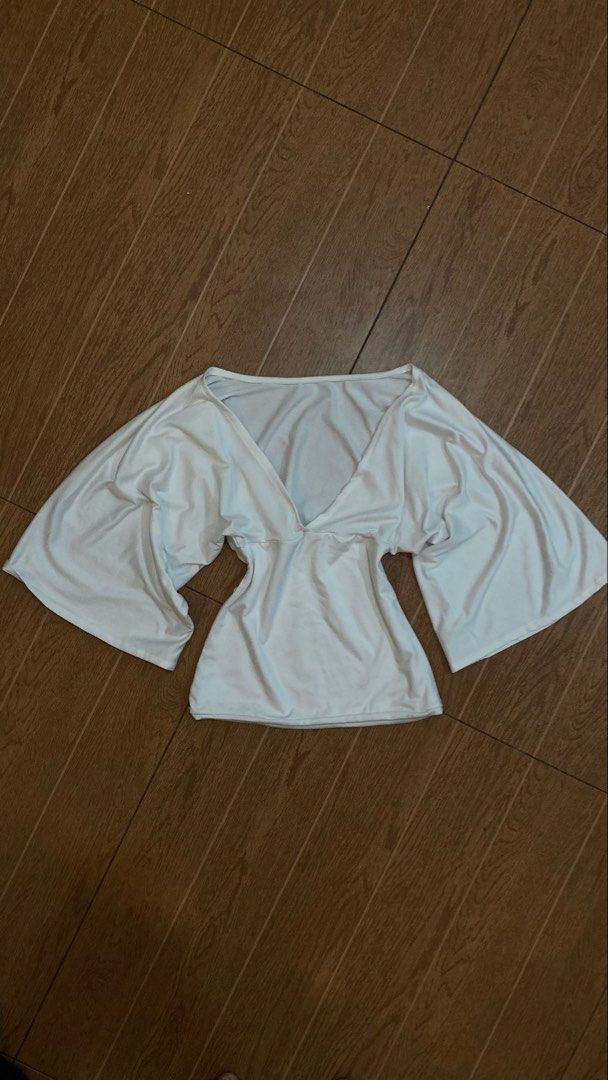 White V-neck top with wide sleeves (Category: Blouses) located in Subic. Submitted by bottomjeanzgals (Listing ID 1468843505, Image 1). Description: - Color: White - Style: Deep V-neckline with trendy wide flare sleeves - Fit: Fitted waist for a flattering silhouette - Material: Soft and comfortable stretch fabric - Condition: Excellent, clean, no stains or damage .