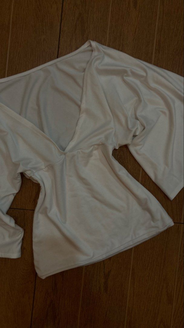 White V-neck top with wide sleeves (Category: Blouses) located in Subic. Submitted by bottomjeanzgals (Listing ID 1468843505, Image 2). Description: - Color: White - Style: Deep V-neckline with trendy wide flare sleeves - Fit: Fitted waist for a flattering silhouette - Material: Soft and comfortable stretch fabric - Condition: Excellent, clean, no stains or damage .