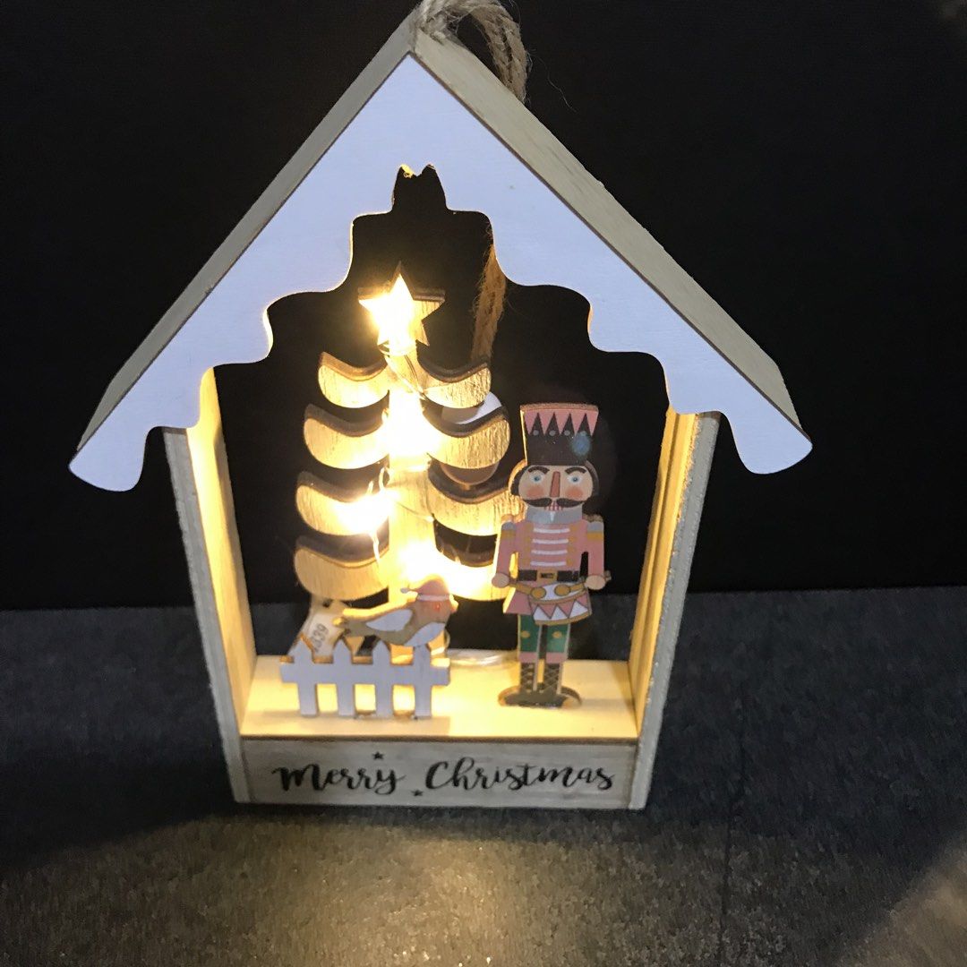 Wooden Christmas House LED Light Nutcracker Tree Decor (Category: Wall Decor) located in Baao. Submitted by all.things.japan (Listing ID 1468753328, Image 3). Description: 7.25 x 5.5 x 1.0 inches - Wooden house-shaped Christmas decor with built-in warm fairy lights - Detailed interior scene featuring a nutcracker soldier, miniature tree, bird, and picket fence - Features a cheerful 'Merry Christmas' greeting on the base - Natural wood frame accen