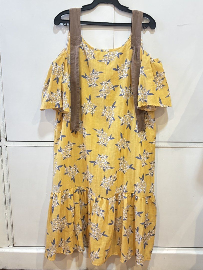 Yellow Floral Cold Shoulder Dress (Category: Dresses) located in Caloocan City. Submitted by joannarms320722 (Listing ID 1468780073, Image 2). Description: - Style: Bright yellow midi dress with white and blue floral print - Design: Cold shoulder cut with ruffled short sleeves and decorative hanging brown straps - Details: Ruffled hem tier at the bottom and lightweight fabric - Fit: Loose, relaxed, and easy slip-on style - Condition: Brand new / 
