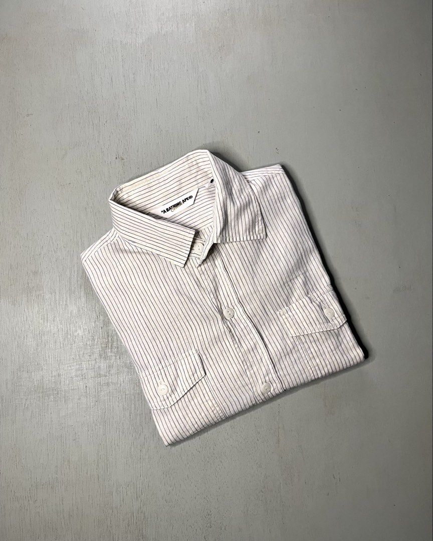 A Bathing Ape BAPE Blue Stripe (authentic) (Category: Tshirts & Polo Shirts ) located in Catbalogan. Submitted by yellfindss (Listing ID 1469131524, Image 1). Description: - 100% Authentic BAPE button-down shirt - Design: White fabric with fine blue vertical stripes -20.5/27 - Material: Lightweight and breathable 86% cotton, 14% linen blend - Origin: Made in Japan by Nowhere Co. - Details: Standard inner wash tags with gold ape head logo attached