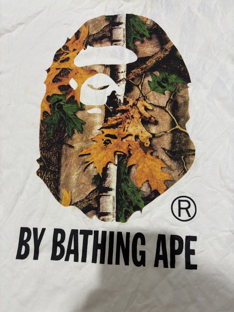 A Bathing Ape Bape Forest Camo Ape Head Tee (Category: Tshirts & Polo Shirts ) located in Daraga. Submitted by hannieldustin (Listing ID 1468981570, Image 2). Description: - Brand: A Bathing Ape (BAPE) - Design: Large Forest Camo Ape Head graphic with 'BY BATHING APE' lettering - Size: Medium (tag on collar) 20x27 - Authenticity details: Standard neck tags and sleeve ape tag included - Condition: Pre-loved with noticeable yellowing and stains aro