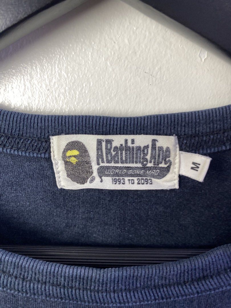 A Bathing Ape BAPE Pocket Tee Navy Size M (Category: Tshirts & Polo Shirts ) located in Manila. Submitted by declutterpromax (Listing ID 1468997486, Image 2). Description: - Brand: A Bathing Ape (Bape) - Color: Dark Blue - Size: Medium (19" across chest, 25" length as shown in photos) - Details: Camo print chest pocket with iconic ape graphic - Authenticity: Features classic Bape neck tags and sleeve tag - Condition: Normal fade from gentle wear.