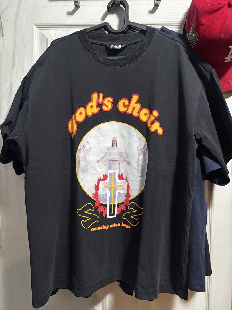 A.A.B God's Choir Graphic Tee Black (Category: Tshirts & Polo Shirts ) located in Quezon City. Submitted by .sachii_ (Listing ID 1469023810, Image 1). Description: - Brand: a.a.b (Amazing Asian Boyz) - Color: Black - Fit: Relaxed fit with crew neck collar - Design: Front graphic features 'God's choir' text, religious illustration, and cross - Detail: Small logo graphic printed on the upper back neckline - Sleeve: Short sleeve.