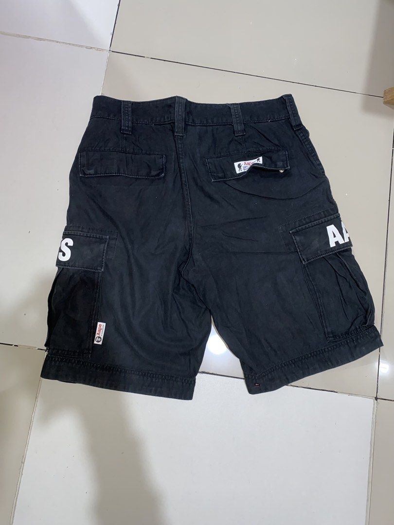 AAPE By A Bathing Ape Black Cargo Shorts Size M (Category: Shorts) located in Manila. Submitted by japhetcond32104 (Listing ID 1469111602, Image 2). Description: - Brand: AAPE by A Bathing Ape - Size: Medium - Color: Black with camo print inner waistband lining - Details: White letter print on side pockets and logo-embossed button closure - Storage: Multiple utility pockets with brand tags - Origin: Made in China - Condition: Shows regular wash w