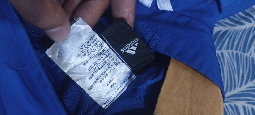 Adidas Blue Windbreaker Jacket (Category: Coats, Jackets and Outerwear) located in Muntinlupa City. Submitted by thriftben (Listing ID 1468930546, Image 3). Description: Blue Adidas windbreaker with white and tan stripes down the sleeves. Bright pink accent line near the cuffs. Full zip closure with zipped side pockets. Stand-up collar. Inner mesh lining. 100% recycled polyester construction. Made in China. Standard men's size M..