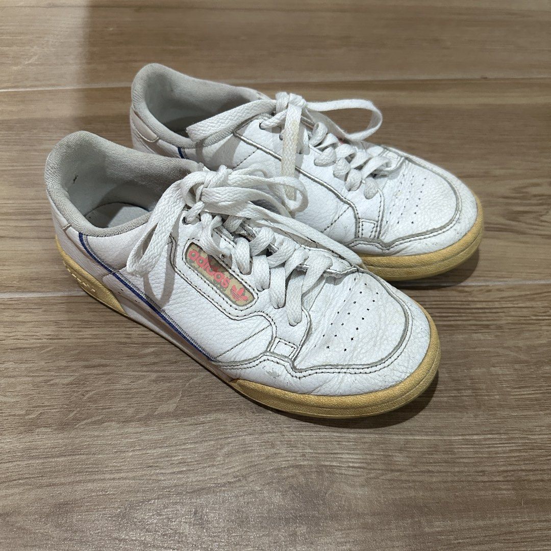Adidas Continental 80 White Sneakers (Category: Sneakers) located in Pasig City. Submitted by nina.declutter (Listing ID 1468990321, Image 3). Description: - Brand: adidas - Color: White with pink branding, and blue/red piping - Material: Leather upper with white laces - Condition: Pre-loved with visible yellowing on soles, toe creasing, and scuffs - Interior: Normal dirt accumulation from regular use PLEASE MANAGE EXPECTATIONS, THIS IS OLD & USE
