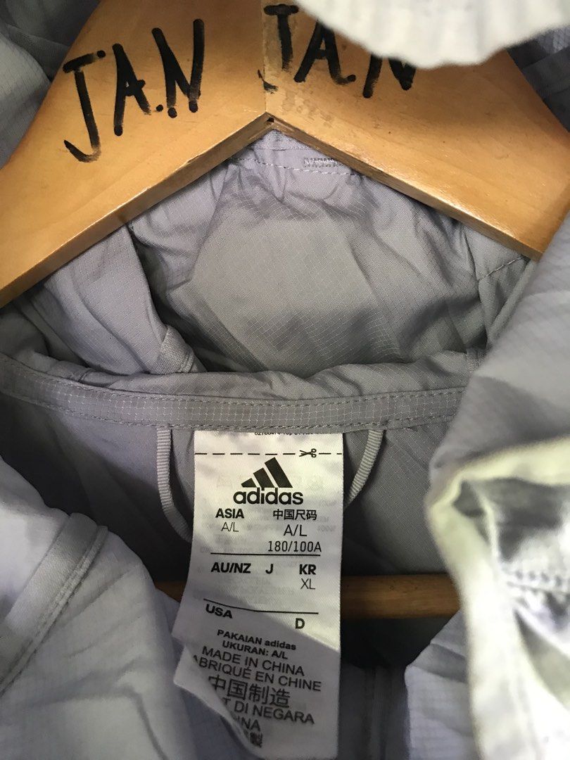 Adidas Grey Hooded Windbreaker Jacket Size L (Category: Coats, Jackets and Outerwear) located in Manila. Submitted by selme.finds (Listing ID 1468975005, Image 3). Description: - Brand: Adidas - Color: Grey - Size: Asia L (180/100A) - Material: Ribbed ripstop fabric - Features: Zip-up front, hood, and vertical zippered chest pocket - Style Code: GJ9949 - Production Date: 05/22 - Made in China - Condition: Excellent, ready to wear!.