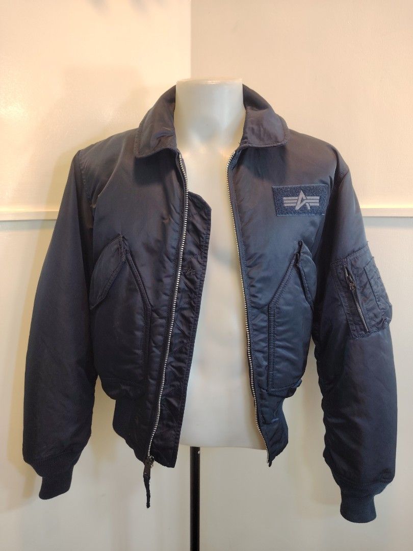 Alpha Industries Navy Blue Bomber Jacket (Category: Coats, Jackets and Outerwear) located in La Trinidad. Submitted by padasem_kadi (Listing ID 1468993323, Image 2). Description: - Brand: Alpha Industries - Color: Navy Blue - Style: Classic bomber jacket with zip-up front and branded hardware - Pockets: Dual front slanted pockets and signature utility pocket on left sleeve with orange tag - Detailing: Chest patch with velcro backing, ribbed colla