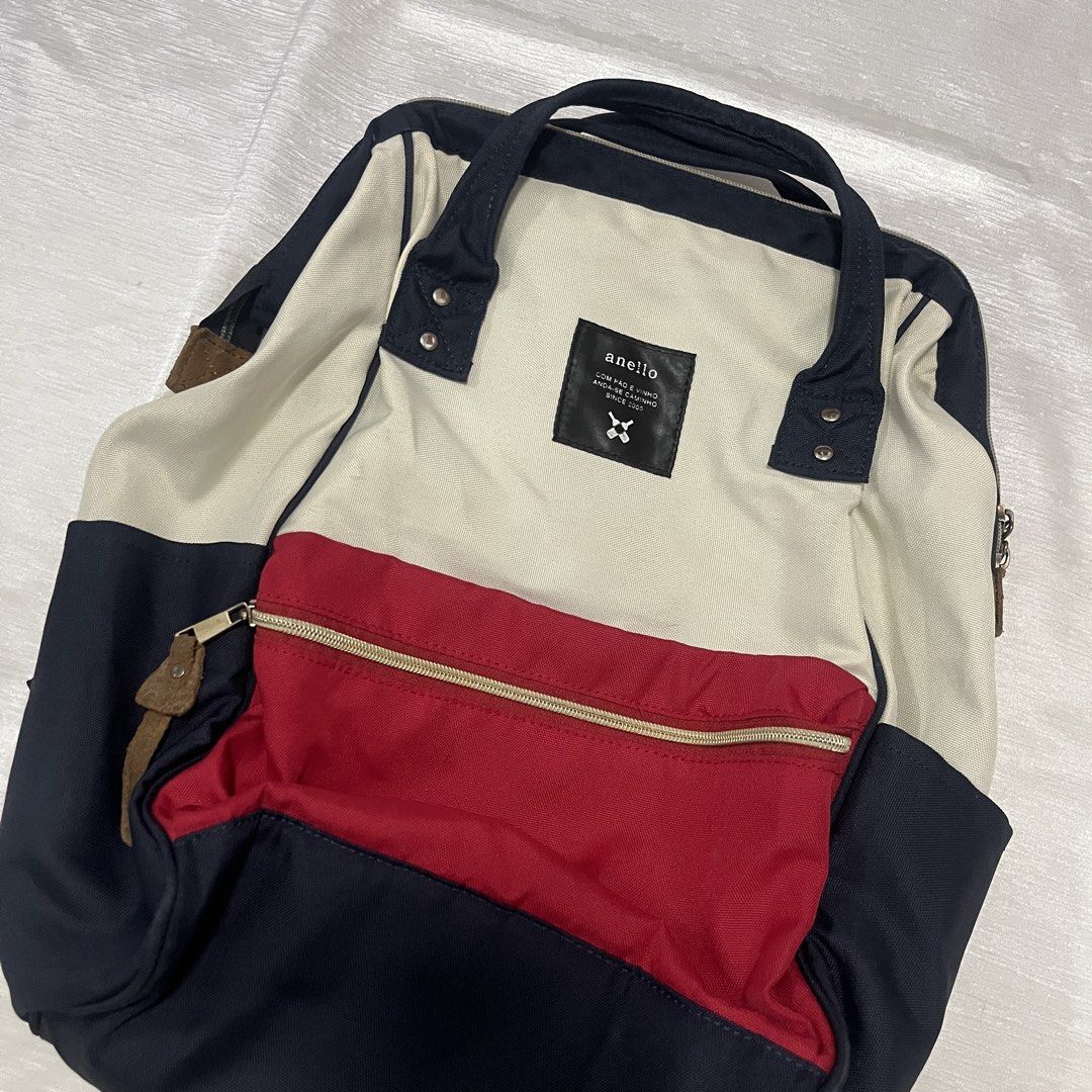 Anello Multi-Color Canvas Backpack (Category: Backpacks) located in Dasmarinas. Submitted by minx203 (Listing ID 1469024600, Image 3). Description: - Brand: Anello - Design: Tri-color (Off-white, Red, Navy Blue) - Material: Sturdy canvas construction - Features: Signature structured frame top opening, front zippered pocket with leather pull tab, double top carry handles, and adjustable padded shoulder straps - Interior: Spacious main compartment 