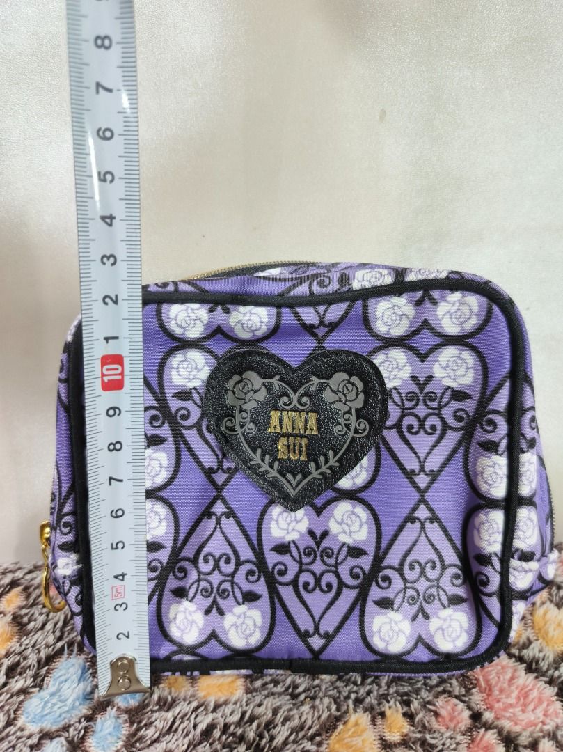 Anna Sui Purple Rose Pattern Cosmetic Pouch (Category: Purses & Pouches) located in San Leonardo. Submitted by burgossanleonardo.12345 (Listing ID 1469078072, Image 3). Description: - Brand: Anna Sui - Design: Purple with black filigree and white rose pattern - Front Detail: Black heart-shaped patch with gold glitter Anna Sui logo - Hardware: Gold zipper with a chic round pull ring - Interior: Solid purple lining with multiple slip pockets and co