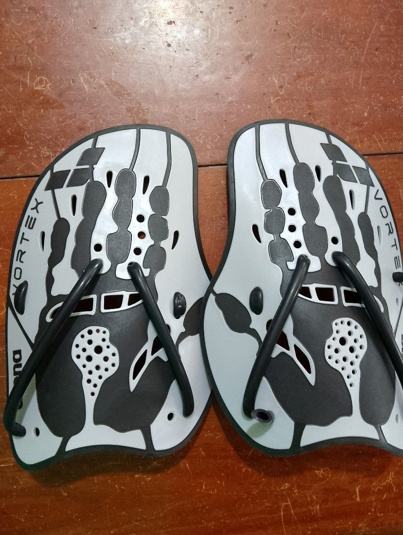 Arena Vortex Swim Paddles (Category: Water Sports) located in Dipolog. Submitted by violetsari2x (Listing ID 1468943734, Image 1). Description: - Model: Arena Vortex Swim Hand Paddles - Color: Grey and white with black rubber straps - Material: Durable plastic construction - Design: Hydrodynamic shape featuring finger holes and cutouts for an enhanced water feel - Purpose: Ideal for pool training sessions to build upper body strength and refine f