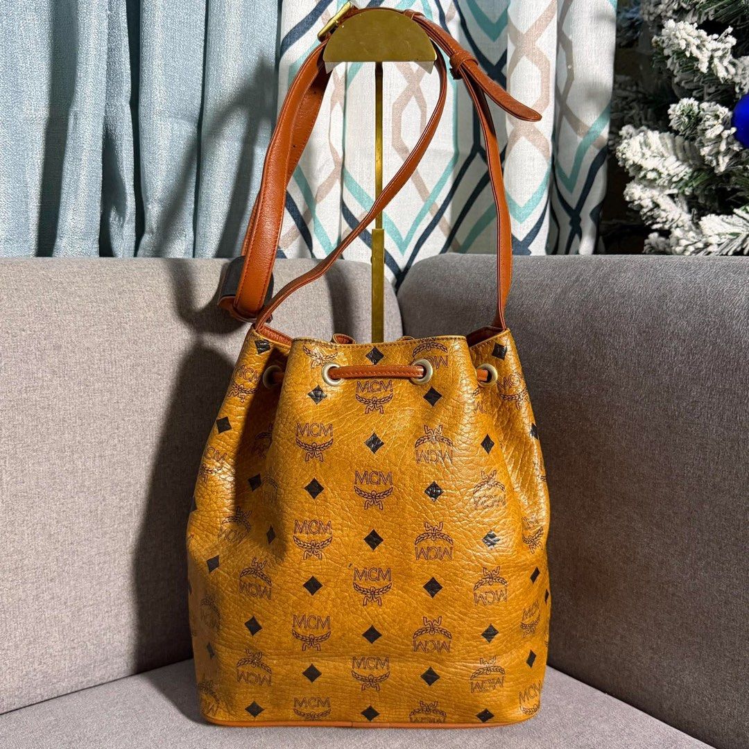 Authentic MCM Visetos Monogram Bucket Bag Cognac (Category: Luxury Bags & Wallets) located in Madrid. Submitted by jhunaceee (Listing ID 1468957562, Image 2). Description: - Authentic MCM bucket bag in classic cognac Visetos monogram coated canvas - Features iconic black and brown diamond pattern with dark brown leather trim - Elegant gold-tone hardware and secure drawstring closure - Adjustable leather shoulder strap for comfortable wear - Struc