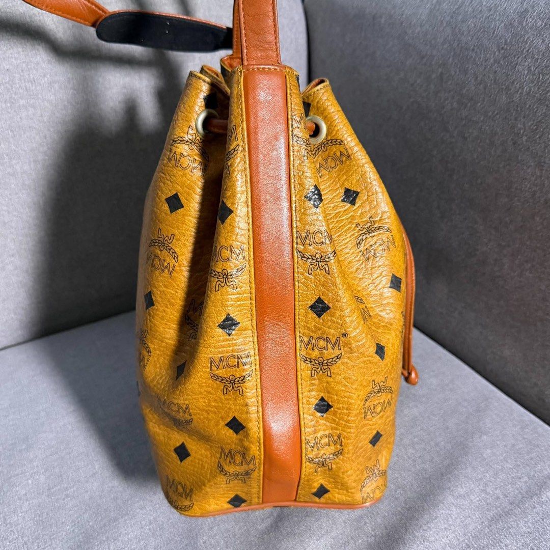 Authentic MCM Visetos Monogram Bucket Bag Cognac (Category: Luxury Bags & Wallets) located in Madrid. Submitted by jhunaceee (Listing ID 1468957562, Image 3). Description: - Authentic MCM bucket bag in classic cognac Visetos monogram coated canvas - Features iconic black and brown diamond pattern with dark brown leather trim - Elegant gold-tone hardware and secure drawstring closure - Adjustable leather shoulder strap for comfortable wear - Struc