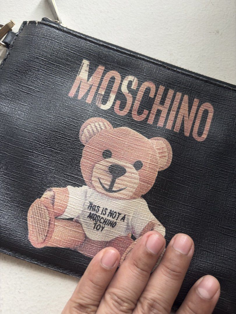 Authentic Moschino Teddy Bear Flat Clutch with Wristlet (Category: Luxury Bags & Wallets) located in Mandaluyong City. Submitted by wear_your_style (Listing ID 1468967946, Image 2). Description: Super nice. This the Couture line of Moschino, the most expensive line. Material is PU or PVC. Malambot naman siya. Inside lining is cloth with 1 zipped secret pocket. Black pa naman. The Teddy Bear is painted on the surface. Approx 9 inches wide and 7.5 
