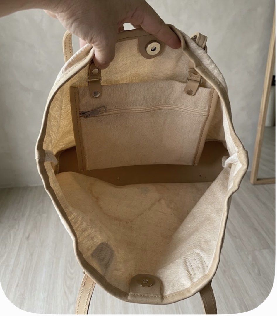 Beige Canvas Tote Bag with Leather Trim (Category: Tote Bags) located in Manila. Submitted by goldenphoenix_ac6904 (Listing ID 1468943948, Image 2). Description: - Color: Neutral beige/cream - Material: Canvas with leather trim - Closure: Top magnetic closure - Storage: Spacious main compartment with interior zippered pocket - Handles: Dual top handles for easy carrying - Condition: Some staining on the interior lining from previous use.