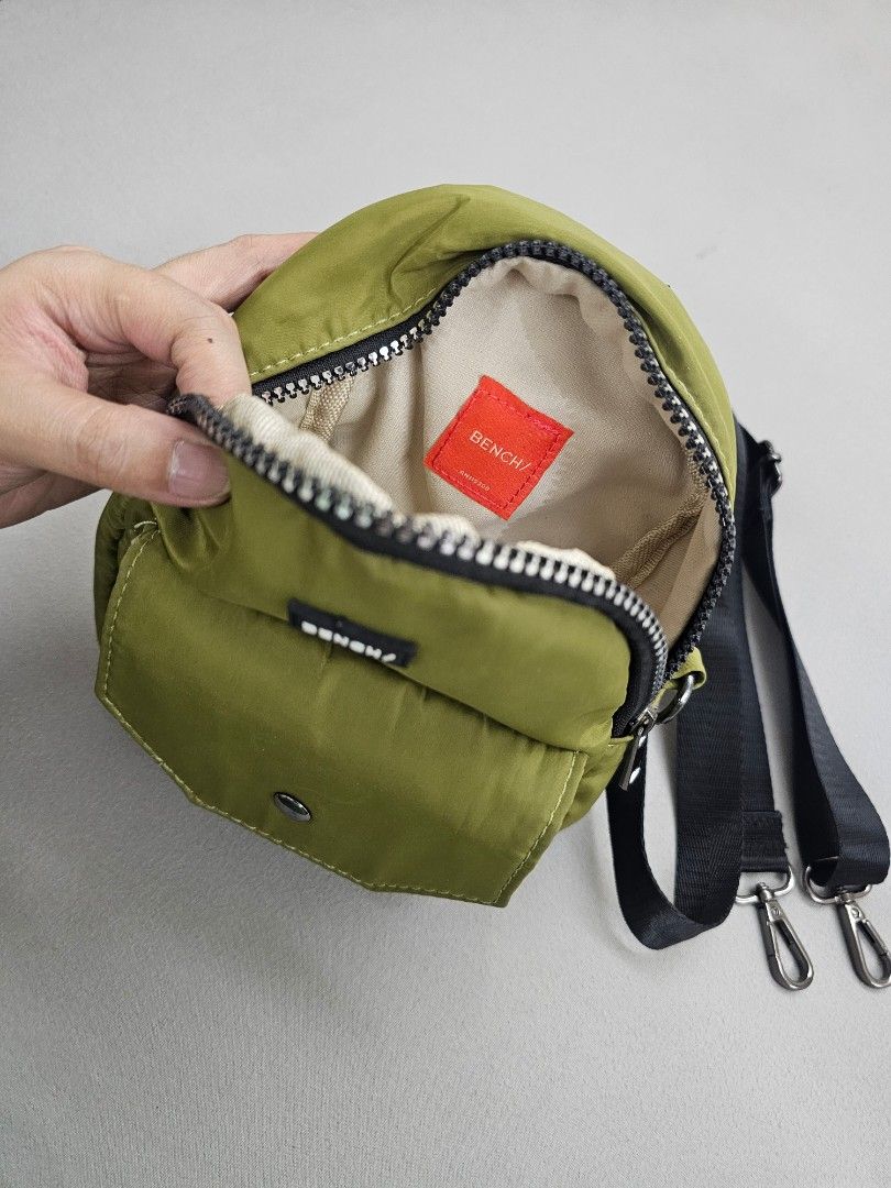 Bench Olive Green Mini Crossbody Bag (Category: Cross-body Bags) located in Marikina City. Submitted by czarinahwithh (Listing ID 1469060687, Image 2). Description: - Brand: Bench - Color: Olive green - Material: Lightweight nylon fabric with beige cloth interior - Compartments: Zippered main compartment and front pocket with snap button closure - Strap: Adjustable black strap with tone metal clasps.