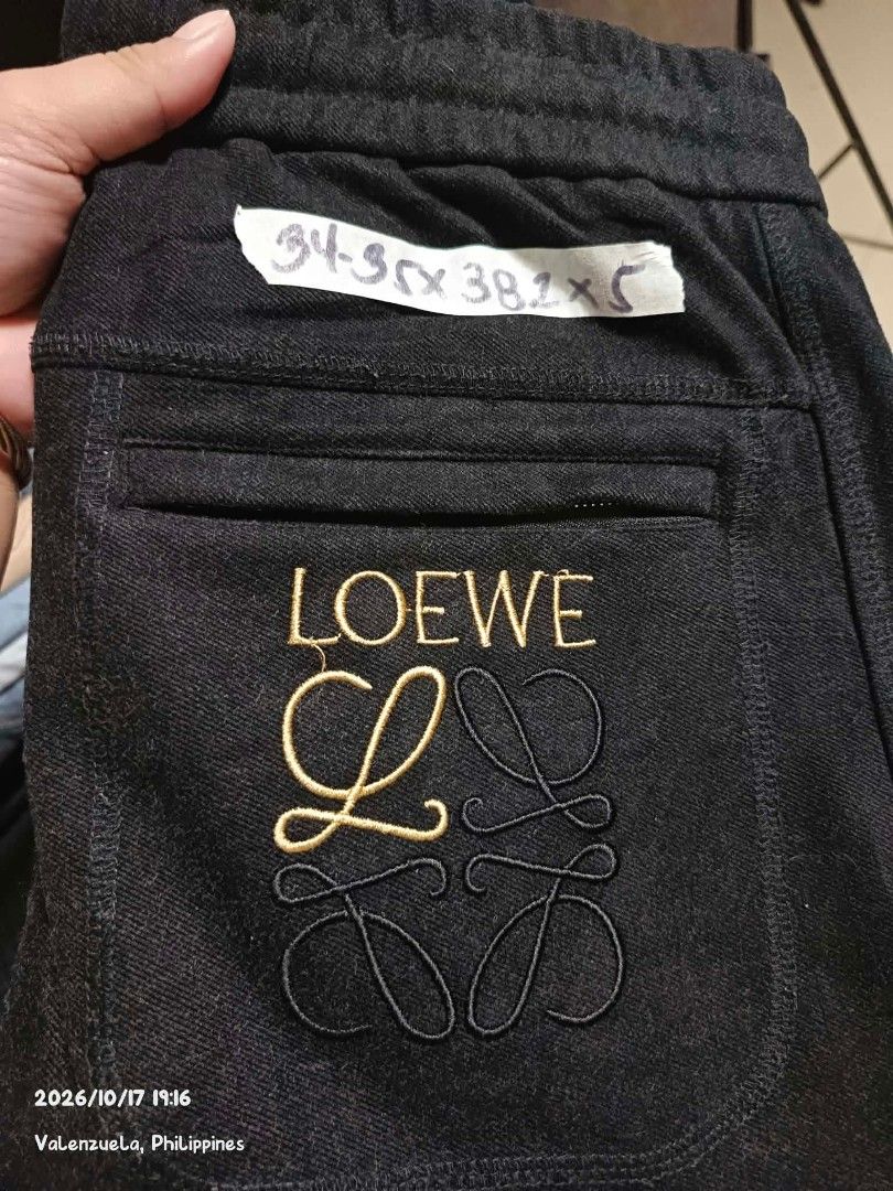 Black Jogger Pants with Embroidery (Category: Joggers) located in Valenzuela. Submitted by AnahThrift (Listing ID 1469061908, Image 1). Description: - Color: Solid black with gold and black stitching - Brand detail: Embroidered Loewe logo on the back pocket - Waist: Adjustable drawstring with branded hardware accents - Pockets: Functional front pockets - Cuffs: Comfortable ribbed ankle cuffs - Perfect for casual wear and daily styling.