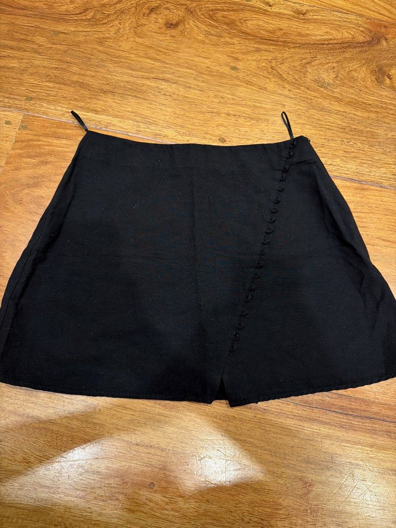 Black mini skirt with button detail (Category: Skirts) located in Quezon City. Submitted by nic.man (Listing ID 1469070531, Image 1). Description: - Color: Black - Style: Wraparound mini skirt with short cut - Details: Diagonal row of matching black fabric buttons, simple waistband with tiny hanging loops - Finish: Clean bottom hem - Versatility: Easy to mix and match with various tops and footwear.