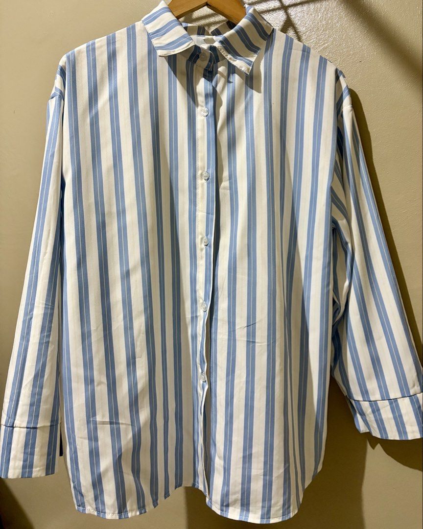 Blue and White Striped Button-Down Shirt (Category: Shirts) located in Caloocan City. Submitted by stella_mari27 (Listing ID 1469100417, Image 2). Description: - Color/Pattern: Blue and white vertical stripes - Design: Long sleeves, front button closure, and classic collar - Fit: Relaxed and comfortable - Material: Lightweight fabric - Styling: Easy to pair with jeans or trousers for casual wear.
