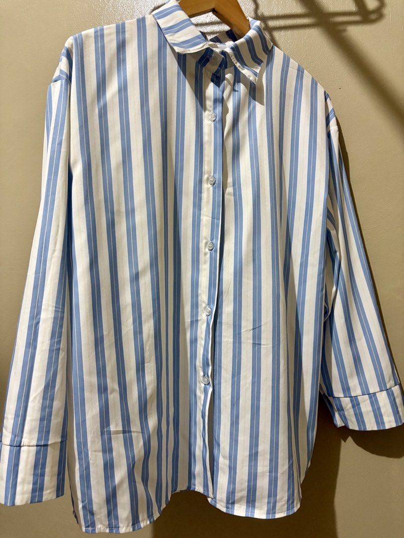 Blue and White Striped Button-Down Shirt (Category: Shirts) located in Caloocan City. Submitted by stella_mari27 (Listing ID 1469100417, Image 1). Description: - Color/Pattern: Blue and white vertical stripes - Design: Long sleeves, front button closure, and classic collar - Fit: Relaxed and comfortable - Material: Lightweight fabric - Styling: Easy to pair with jeans or trousers for casual wear.