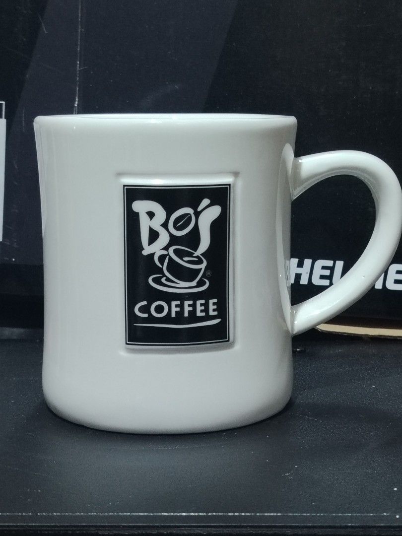Bo's Coffee Ceramic Mug White (Category: Coffee & Tea Tableware) located in Quezon City. Submitted by epicart (Listing ID 1468975424, Image 1). Description: - Authentic Bo's Coffee ceramic mug - Classic white finish with a stylish raised black rectangular logo - Hand-made exclusively for Bo's Coffee - Sturdy build with a solid, comfortable handle - Clean interior, ready for your daily coffee or tea Medium size.
