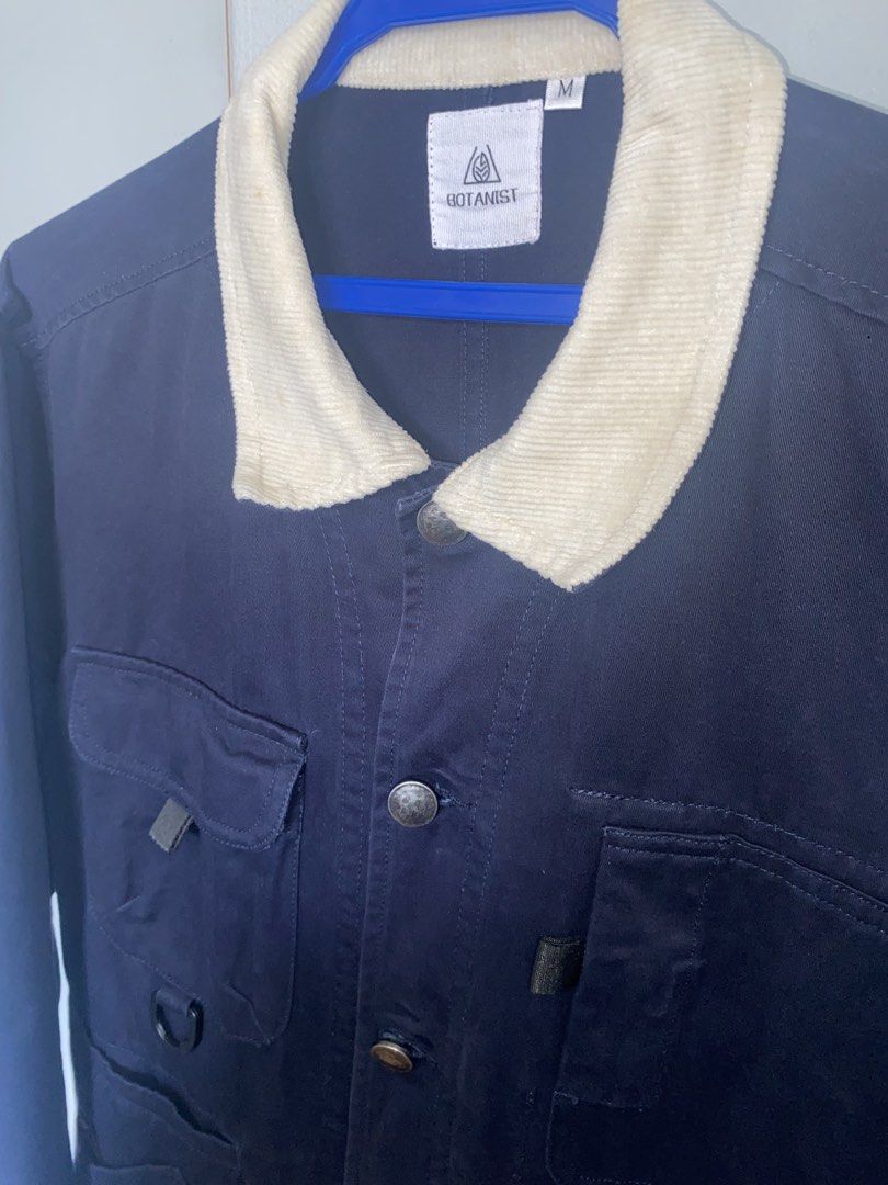 Botanist Navy Chore Jacket (Category: Coats, Jackets and Outerwear) located in Manila. Submitted by antonvarga38504 (Listing ID 1468983473, Image 3). Description: - Brand: Botanist - Color: Navy Blue - Size: Medium - Design details: Contrasting white corduroy collar and round elbow patches on both sleeves - Closure: Button-up front with metallic buttons - Pockets & Features: Multiple utility pockets on the chest and lower front, plus a functional