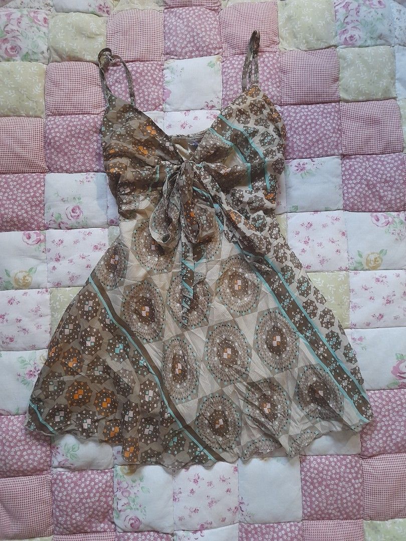 Brown patterned sleeveless top with straps and tie front (Category: Dresses) located in Baguio. Submitted by rei246810173500 (Listing ID 1469064468, Image 1). Description: - Brown and beige patterned dress with geometric circles and diamond motifs - Lightweight and comfortable fabric - Thin shoulder straps with a stylish draped tie detail in the front - Eye-catching turquoise blue stripe accents across the chest and hem - Flared skirt section tha