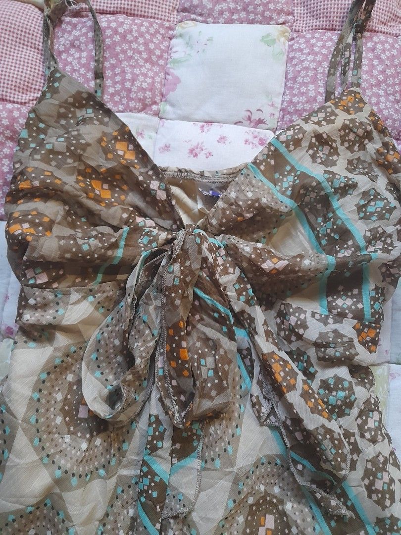 Brown patterned sleeveless top with straps and tie front (Category: Dresses) located in Baguio. Submitted by rei246810173500 (Listing ID 1469064468, Image 2). Description: - Brown and beige patterned dress with geometric circles and diamond motifs - Lightweight and comfortable fabric - Thin shoulder straps with a stylish draped tie detail in the front - Eye-catching turquoise blue stripe accents across the chest and hem - Flared skirt section tha