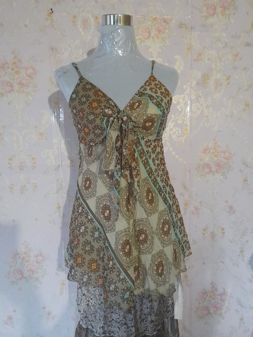 Brown patterned sleeveless top with straps and tie front (Category: Dresses) located in Baguio. Submitted by rei246810173500 (Listing ID 1469064468, Image 3). Description: - Brown and beige patterned dress with geometric circles and diamond motifs - Lightweight and comfortable fabric - Thin shoulder straps with a stylish draped tie detail in the front - Eye-catching turquoise blue stripe accents across the chest and hem - Flared skirt section tha