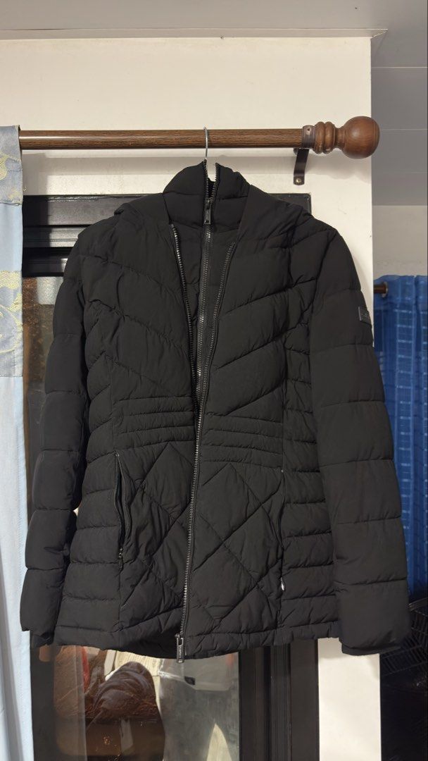 Calvin Klein Infinite Stretch Black Puffer Jacket (Category: Coats, Jackets and Outerwear) located in Manaoag. Submitted by rsnt31 (Listing ID 1469083182, Image 1). Description: - Brand: Calvin Klein (Infinite Stretch Line) - Color: Solid Black - Features: Hooded, zip-up front with branded pull, rubber logo patch on sleeve - Design: Quilted lower front with chevrons above - Condition: Clean fabric, smooth working zipper - Perfect for winter weath
