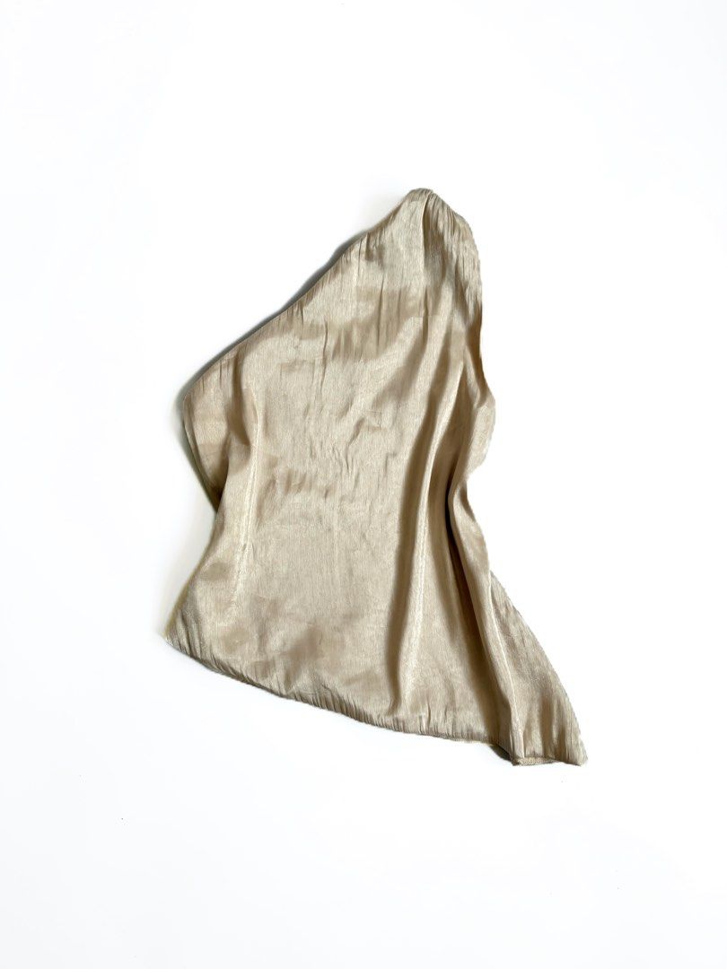 Champagne Satin One-Shoulder Asymmetric Top (Category: Sleeveless) located in Tarlac. Submitted by kr_closet (Listing ID 1468934459, Image 1). Description: - Color: Champagne gold tone - Style: One-shoulder neckline with trendy asymmetric hem - Material: Lightweight, silky fabric with a subtle sheen - Condition: Brand new with tag still attached, clean with no stains or pulls - Versatility: Easy to tuck into skirts or high-waisted pants.