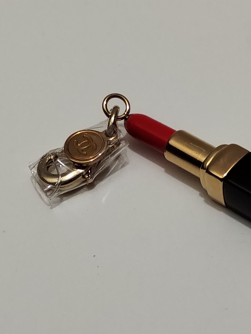 Chanel Lipstick Charm Gold Black Red (Category: Makeup) located in Quezon City. Submitted by kinopipanda (Listing ID 1469029803, Image 2). Description: - Authentic Chanel lipstick charm with gold hardware - Chic black base and vibrant red tip design - Features the classic CC logo stamped on the clasp tag - Brand new, still wrapped in protective plastic - Versatile clip-on style, perfect for bags or bracelets.