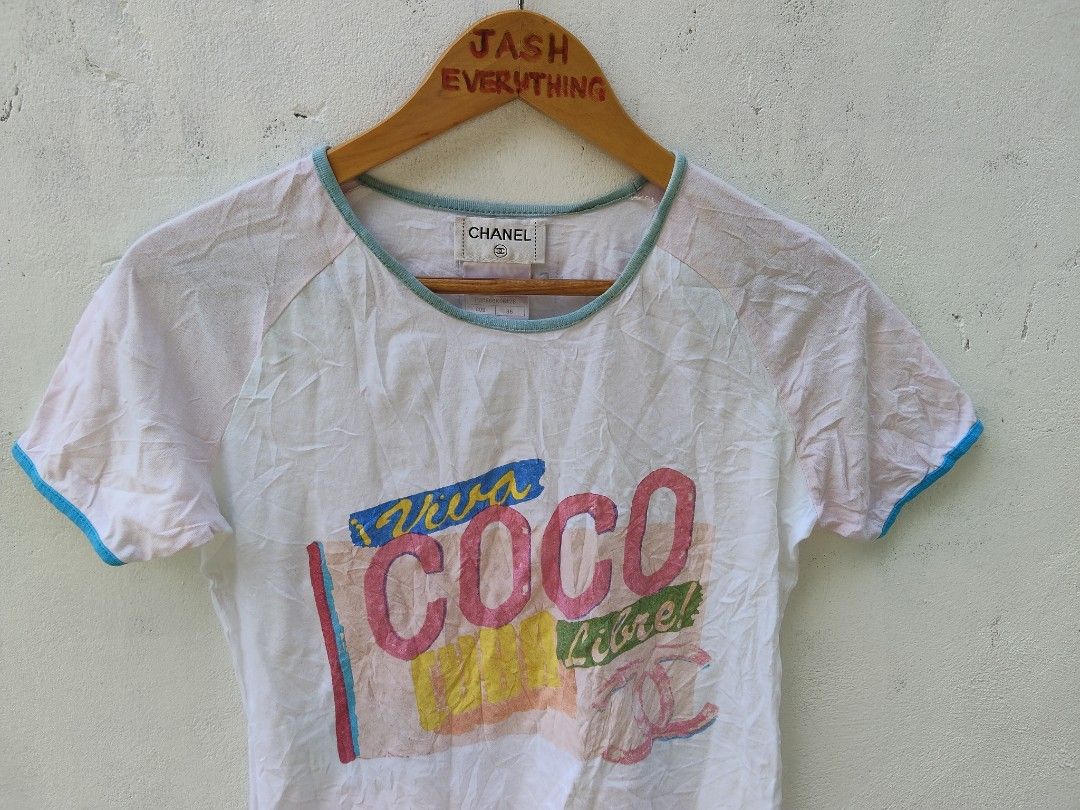 Chanel Viva Coco Libre Graphic Raglan T-Shirt (Category: Shirts) located in City of Isabela. Submitted by jasheverything (Listing ID 1468946546, Image 2). Description: - Brand: Chanel Vintage - Color: White and light pink with contrasting blue trim - Design: 'Viva COCO Libre!' large graphic print on front - Material: 100% cotton, Made in France - Size: 36 (Regular fit, short sleeves) - Condition: Excellent collector's item with unique typography 