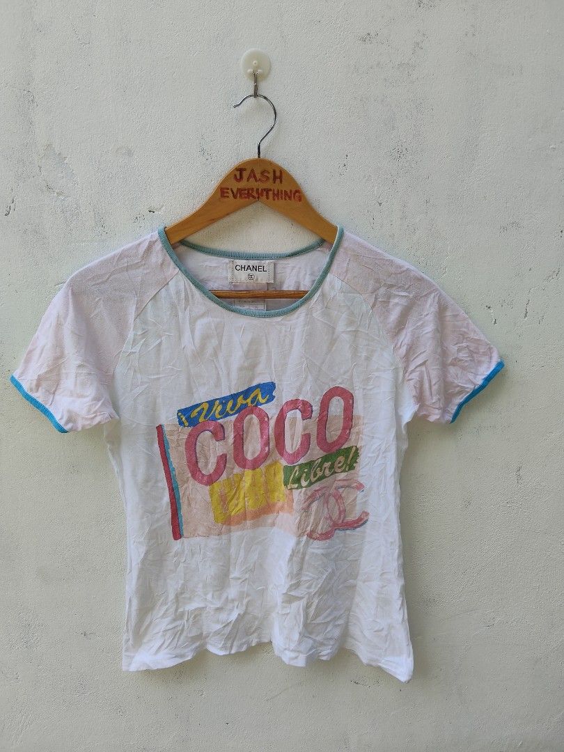 Chanel Viva Coco Libre Graphic Raglan T-Shirt (Category: Shirts) located in City of Isabela. Submitted by jasheverything (Listing ID 1468946546, Image 1). Description: - Brand: Chanel Vintage - Color: White and light pink with contrasting blue trim - Design: 'Viva COCO Libre!' large graphic print on front - Material: 100% cotton, Made in France - Size: 36 (Regular fit, short sleeves) - Condition: Excellent collector's item with unique typography 