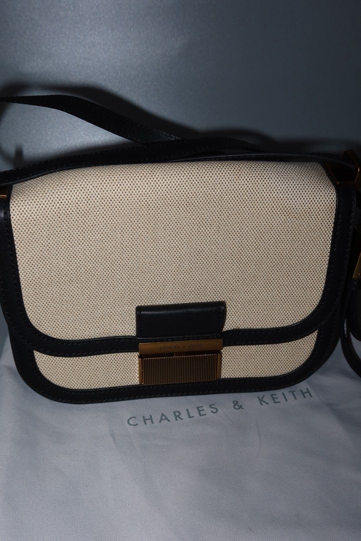 Charles & Keith Black and Beige Shoulder Bag (Category: Shoulder Bags) located in General Trias. Submitted by laiyieeeee (Listing ID 1469011306, Image 3). Description: - Brand: Charles & Keith - Style: Shoulder bag with clean lines and a classic two-tone look - Color/Material: Beige canvas with black trim - Hardware: Elegant gold-tone push-lock closure on front flap - Strap: Adjustable black strap for a comfortable fit - Inclusion: Comes with its