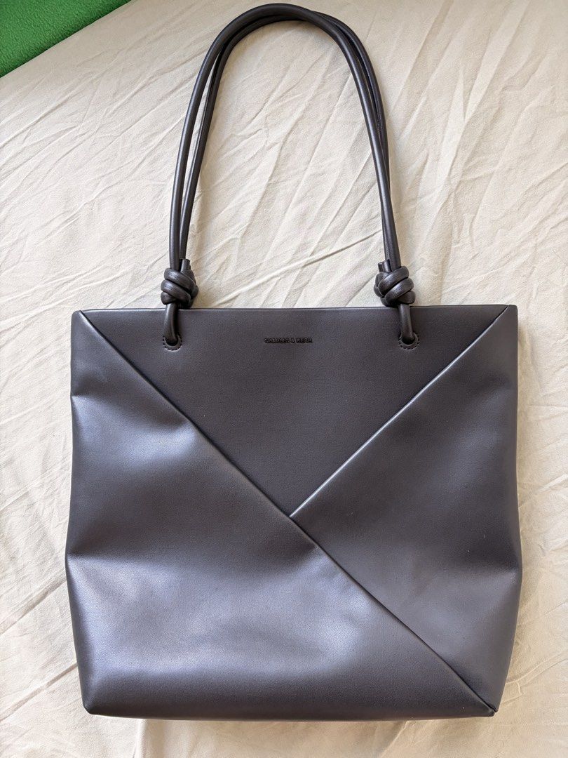 Charles & Keith Dark Brown Folded Tote Bag (Category: Tote Bags) located in Taguig. Submitted by jesrm (Listing ID 1469160615, Image 1). Description: - Brand: Charles & Keith - Color: black - Material: Structured faux leather - Design: Unique folded panel on front with minimalist branding - Straps: Double shoulder straps with stylish knotted base details - Interior: Roomy and spacious, fits everyday essentials, documents, or small laptops - Versa