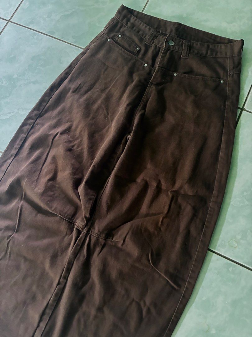 Choco Brown Baggy Barrel Pants (Category: Jeans) located in Batangas. Submitted by jinventoryarchive (Listing ID 1469059254, Image 2). Description: Waist: 32 Length: 41 Leg Op: 11 Thigh: 14 - Rich brown denim with a modern curved barrel leg cut - Mid-rise waist featuring belt loops and a metal button closure - Eye-catching asymmetrical front pocket layout with contrast stitching - Signature leather brand patch on the back waistband - Relaxed silh