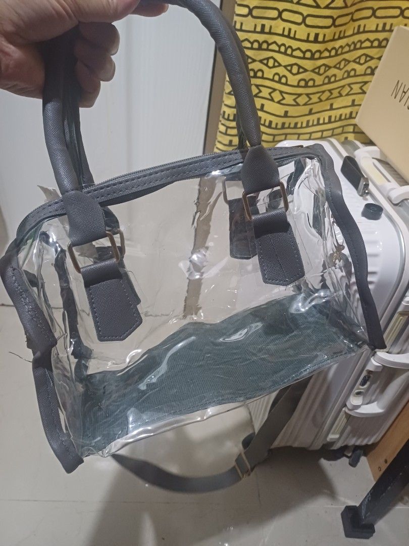Clear transparent handbag with grey trim and shoulder strap (Category: Cross-body Bags) located in Imus. Submitted by bagginholicetc. (Listing ID 1469002043, Image 1). Description: Flaws- sira yung zipper paayos nyo na lang. - Color/Detail: Clear bag with chic grey trim and gold-tone hardware - Closure: Top zipper closure to keep your belongings secure - Versatile Carry: Includes dual top handles and a detachable long shoulder strap - Perfect For