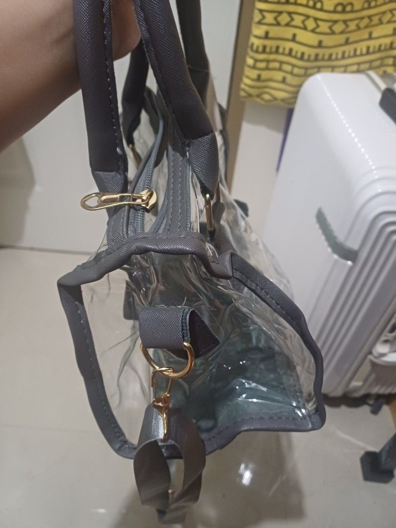 Clear transparent handbag with grey trim and shoulder strap (Category: Cross-body Bags) located in Imus. Submitted by bagginholicetc. (Listing ID 1469002043, Image 2). Description: Flaws- sira yung zipper paayos nyo na lang. - Color/Detail: Clear bag with chic grey trim and gold-tone hardware - Closure: Top zipper closure to keep your belongings secure - Versatile Carry: Includes dual top handles and a detachable long shoulder strap - Perfect For