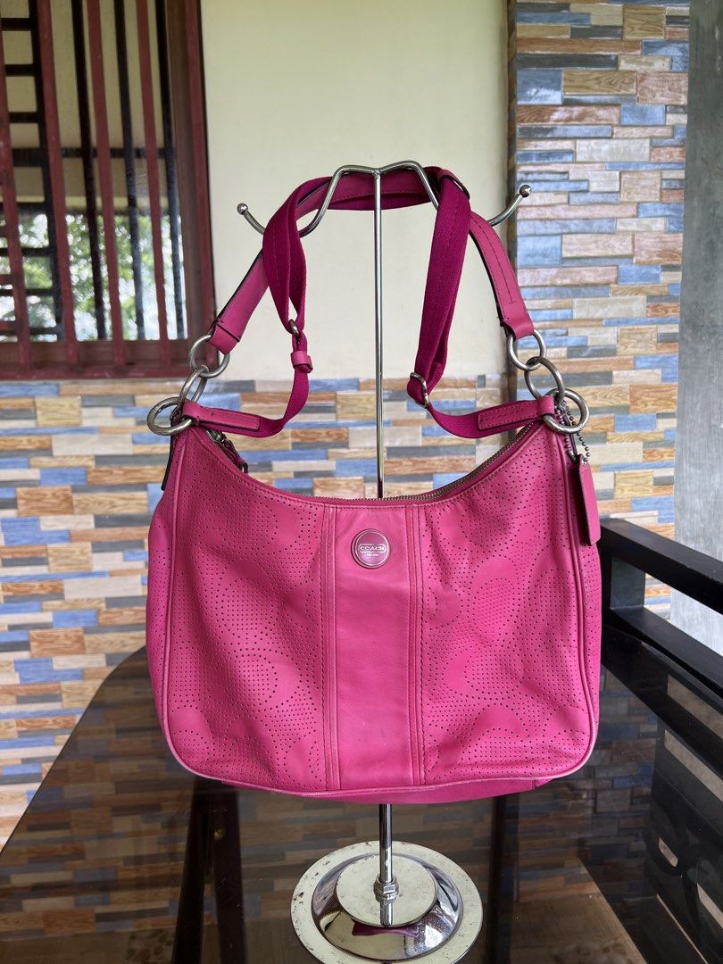 Coach Pink Perforated Leather Shoulder Bag (Category: Luxury Bags & Wallets) located in Iba. Submitted by saploot (Listing ID 1469114976, Image 1). Description: Bright pink Coach shoulder bag with perforated design throughout. Front round metal logo plate reads Coach Est. 1941. Fabric strap with adjustable buckle, matching leather hangtag attached to hardware rings. Zip top closure. Silver-tone hardware..